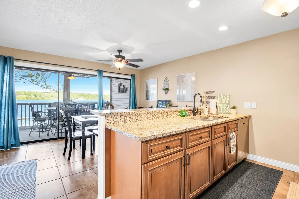 A welcoming interior shot with a granite countertop, lake view, dining area, and decorative signs. The scene feels bright, cheerful, and social, with natural light streaming in and a view that connects guests to the lake’s energy.