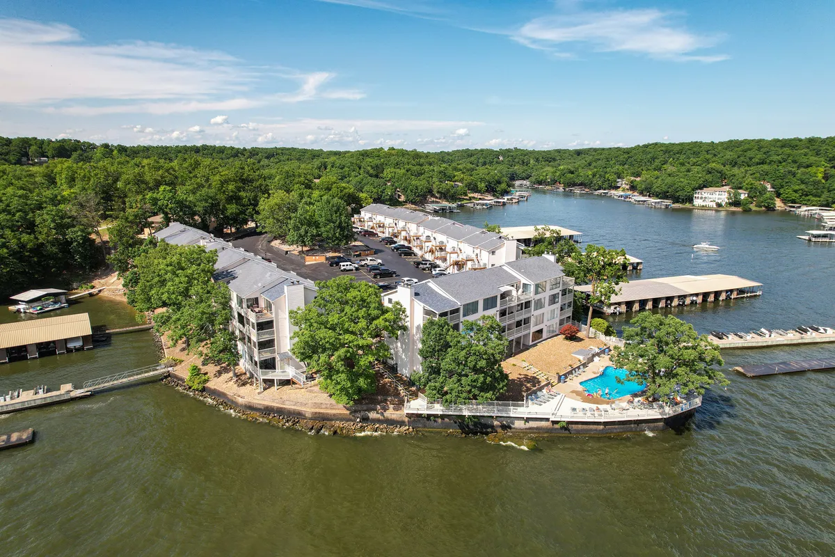 A relaxing exterior view showcasing the lake, pool area, lush greenery, and boat docks, with people enjoying swimming, boating, and picnicking. The image conveys a tranquil, vacation-like mood and highlights the proximity of all key outdoor amenities.