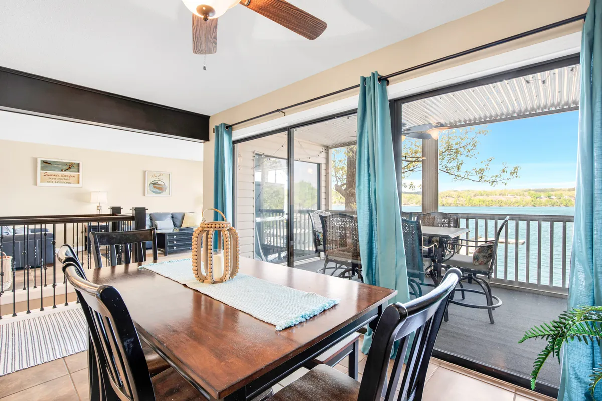 A cozy dining area set beside large glass doors, showing a dining table, ceiling fan, decorative lantern, and a glimpse of the view outside. The area is inviting and ideal for group meals, laughter, and winding down together after a day out.