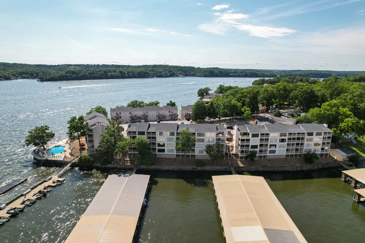 This exterior image captures the main channel of the lake with resort buildings nestled along the shoreline. A sparkling pool, docks, and lush greenery set a tranquil scene, inviting guests to swim, boat, or simply bask in the lakeside serenity. The sunset hues reflected in the water evoke the promise of scenic retreats and peaceful evenings.